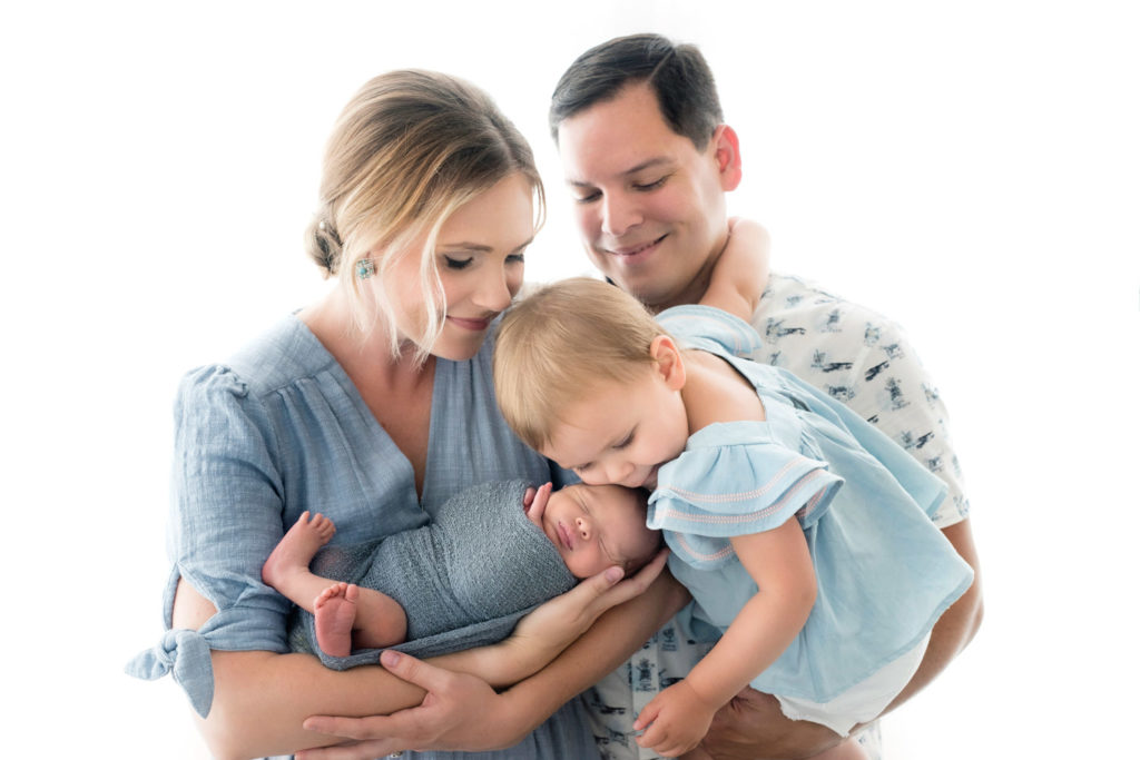 Caucasian family of 4 wearing tones of blue for a newborn photography session