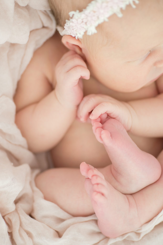 Close up of sleeping newborn’s fingers and toes in professional photo.