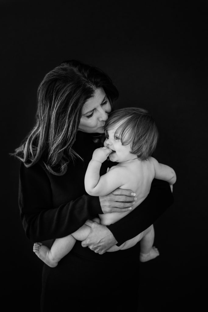 A grandmother and her baby grandson pose together in a studio