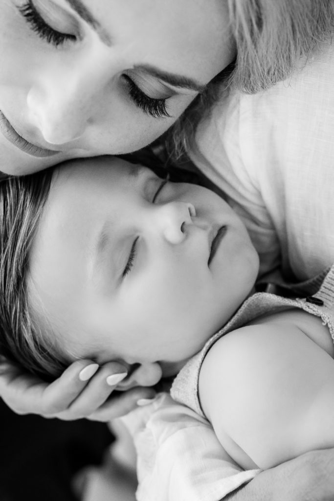 A mom puts her face up against her sleeping baby