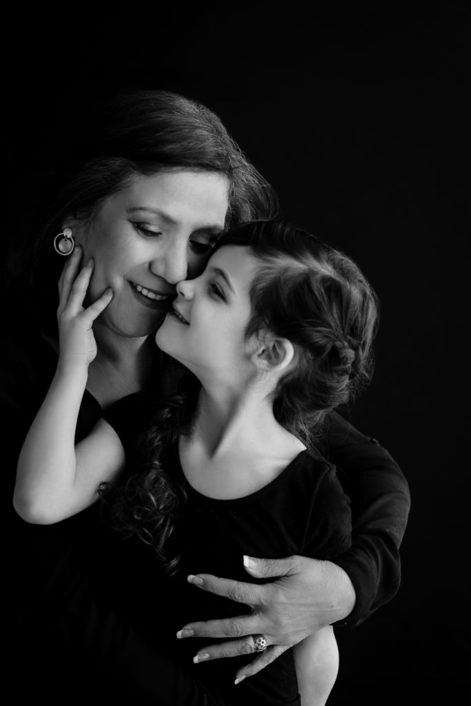 [Black and white photo of  mom and her daughter with their faces together smiling)
