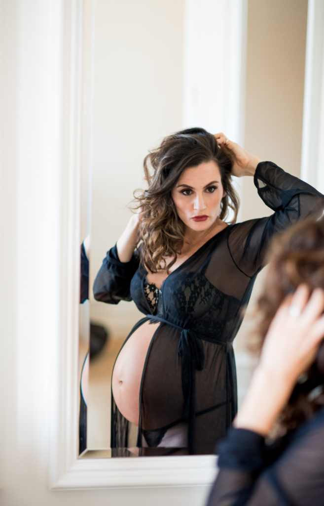 pregnant woman in black robe with black lingerie under fixes hair in the mirror in DC photos