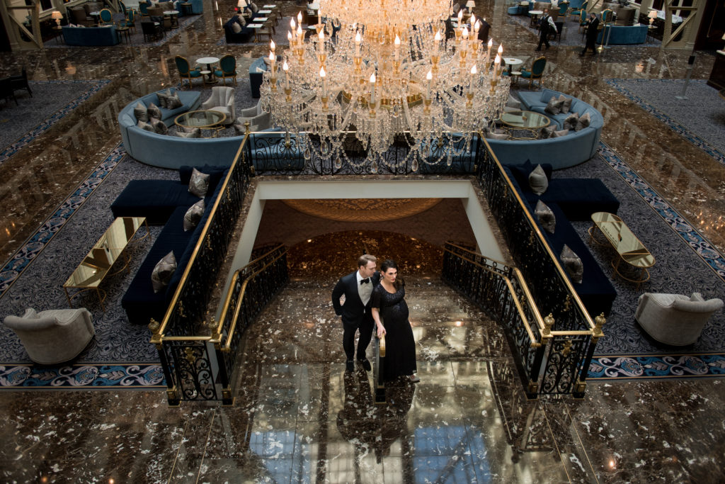 photo of hotel lobby from above with crystal chandelier and husband and wife posing for maternity photo