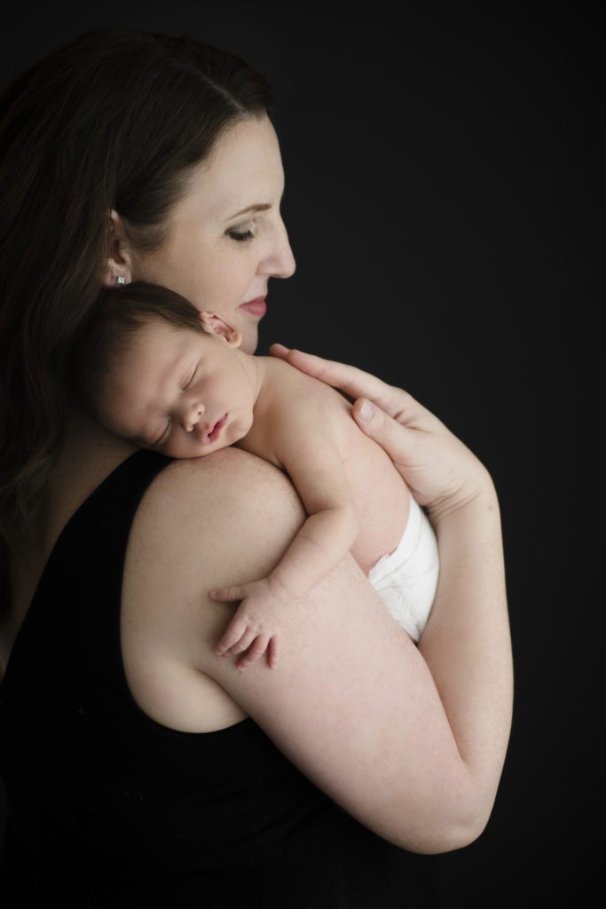 mom hold newborn baby asleep on shoulder 