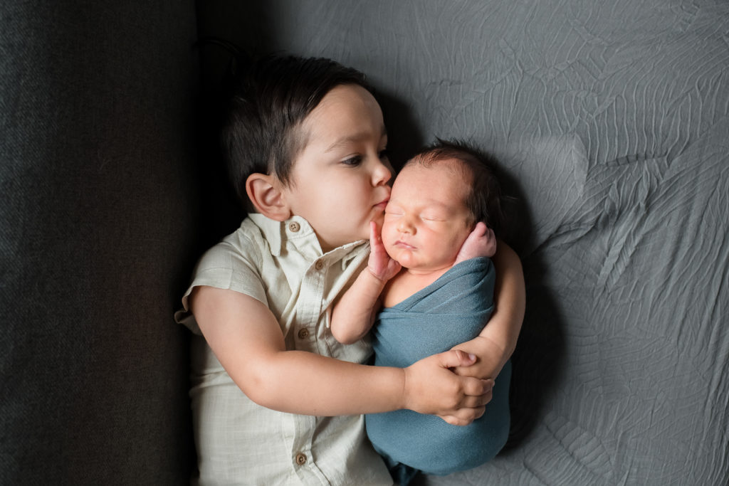Big brother kisses newborn brother 