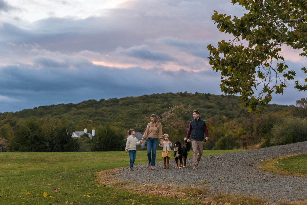 A family walking down a gravel path with fall colors around them 