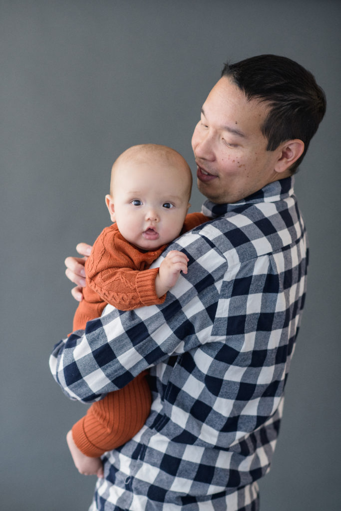 baby held by dad looks at camera during photo session